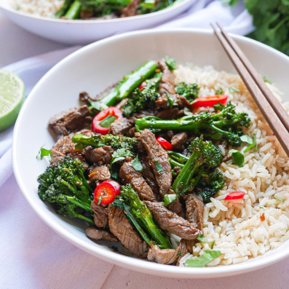 Vietnamese Beef & Broccoli Stir Fry served with rice and garnished with red chillis, in a white bowl