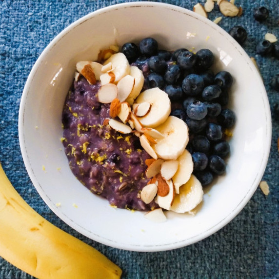 Wild blueberry oatmeal garnished with bananas, blueberries, almonds and lemon zest