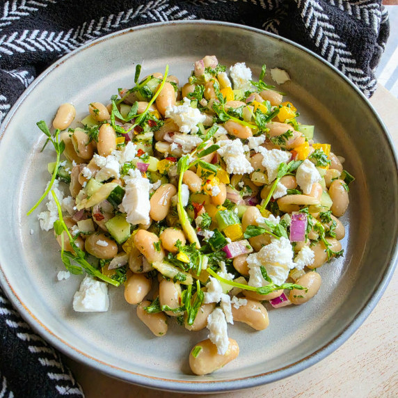 A colourful assortment of beans & veggies in a rimmed bowl against a black towel