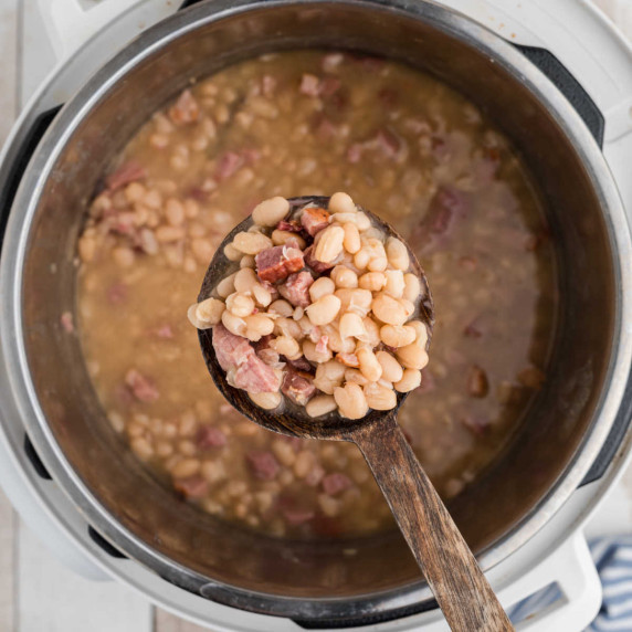 instant pot with beans and ham with a spoon showing contents
