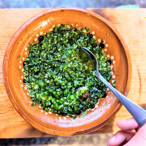 zhoug sauce in a clay bowl on a wooden cutting board