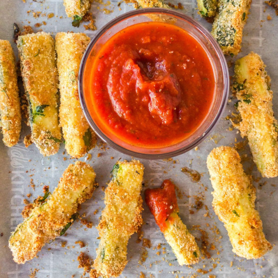 Zucchini fries on a pan overhead with marinara in a bowl to dip.