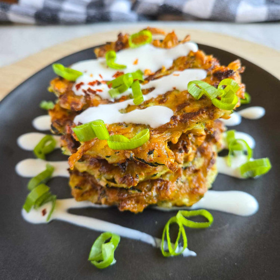 Golden brown fritters drizzled with white sour cream and green onions.