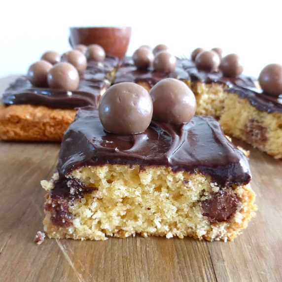 Close up of a cookie bar with chocolate frosting and Maltesers