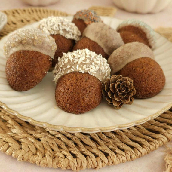 Plate of mini acron shaped chai gingerbreas cakes, topped with spiced glaze on beige plate.