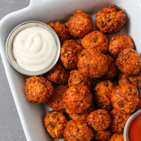 A dish of crispy air fried buffalo cauliflower bites with ranch dressing on the side