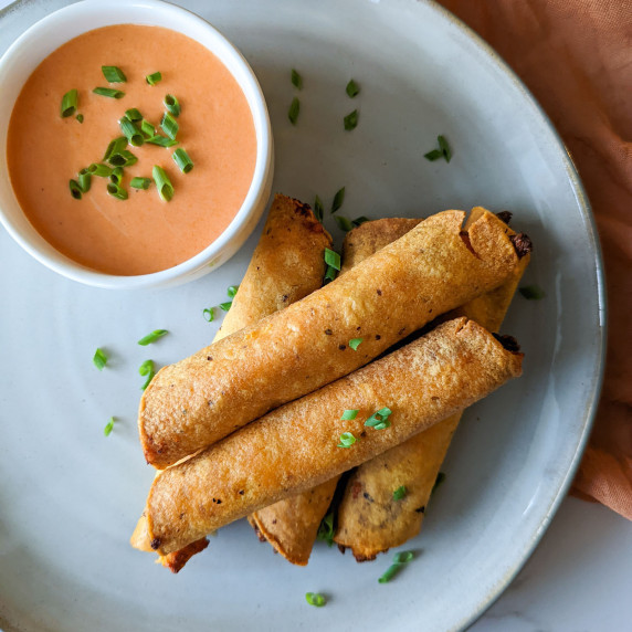A plate of crispy buffalo chicken taquitos served with buffalo ranch dipping sauce