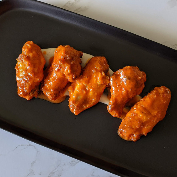 Spicy buffalo wings served on a platter with ranch