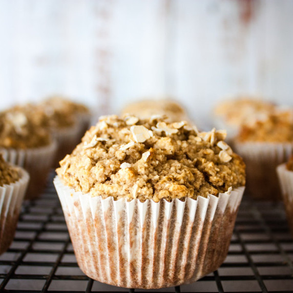 A closeup side view of a baked apple oat muffin on a cooling rack.