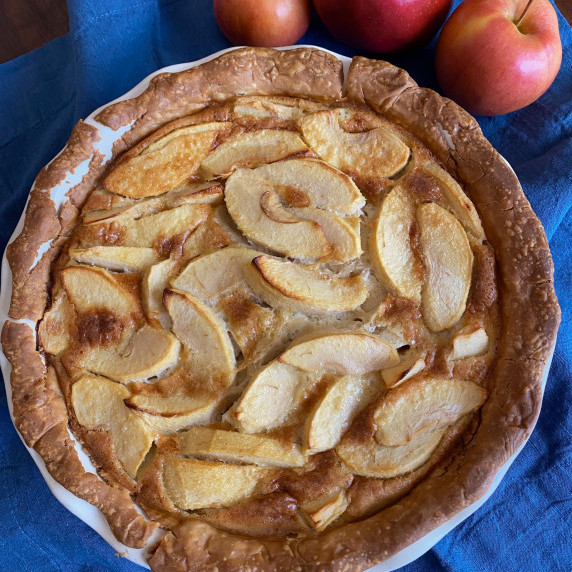 apple pie served in a dish, apples surrounding it
