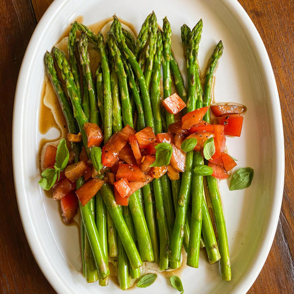 Asparagus with Tomatoes and balasamic vinaigrette on a white plate