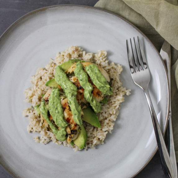 Avocado cilantro lime chicken breast on a bed of brown rice and sliced avocado