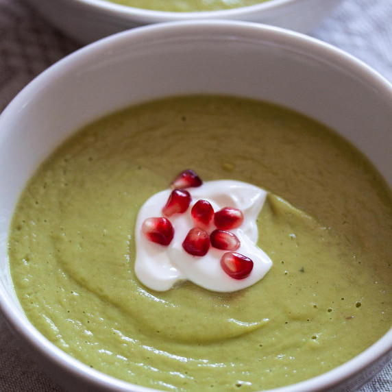 green avocado soup with sour cream, pomegranate in a white dish