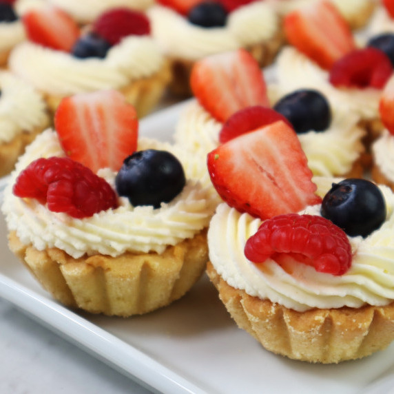 Shortcrust tartlets with light coloured filling and berries. 