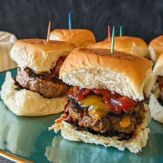 Mini barbecue bacon cheeseburger sliders on Hawaiian rolls on a serving platter