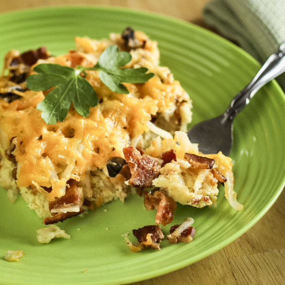 Side shot of a slice of breakfast casserole on a green plate with a fork taking a piece.