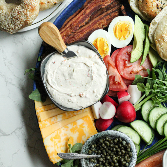 Bagel brunch board with fresh veggies, fruits, proteins, snacks, etc.