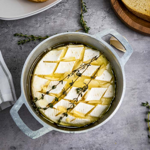 Overhead shot of baked brie garnished with fresh thyme in a small baking dish with more thyme sprigs