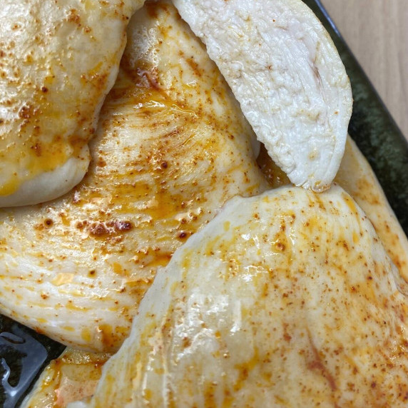 A close up view of a pile of baked chicken breasts with paprika seasoning.