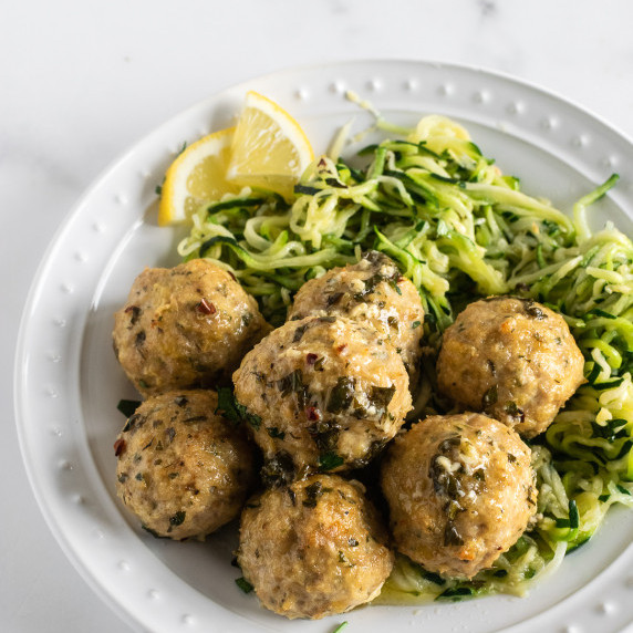 baked chicken meatballs on white plate with zucchini noodles