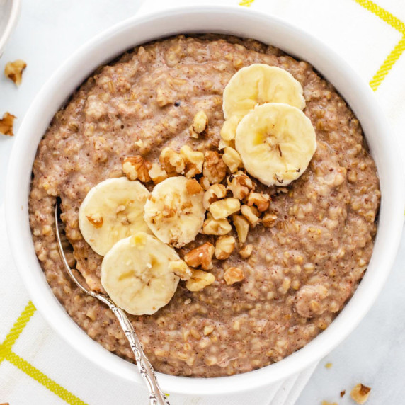 Banana steel cut oats in a bowl with sliced bananas and chopped walnuts.