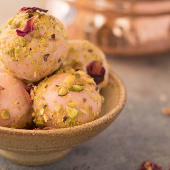 rose truffles rolled in pistachios and rose petal in a small bowl
