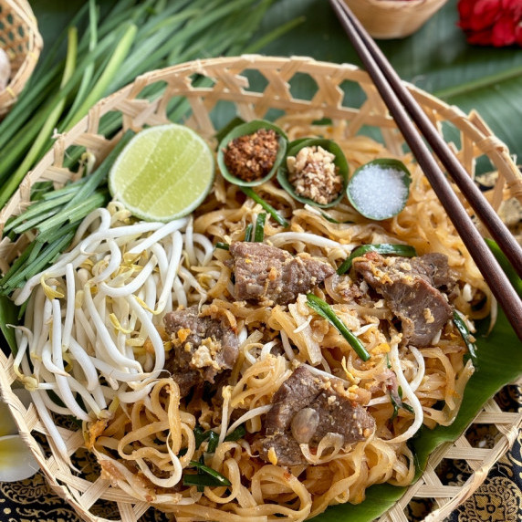 Authentic beef pad Thai served in a bamboo woven dish.