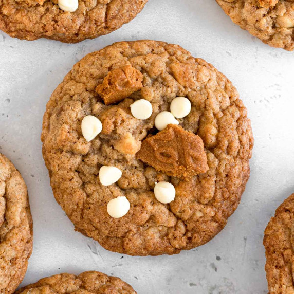 Biscoff oat cookies topped with white chocolate chips arranged on a light surface.