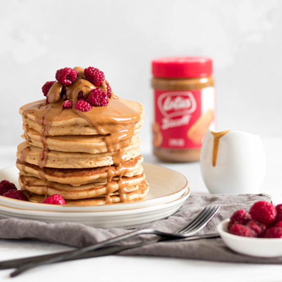 A stack of Biscoff pancakes topped with melted Biscoff spread and raspberries.