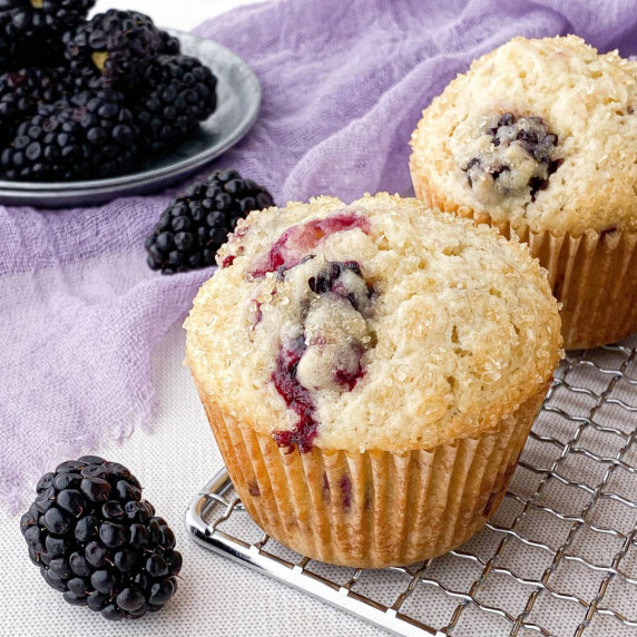 Closeup of Blackberry Buttermilk Muffin with fresh blackberries nearby.