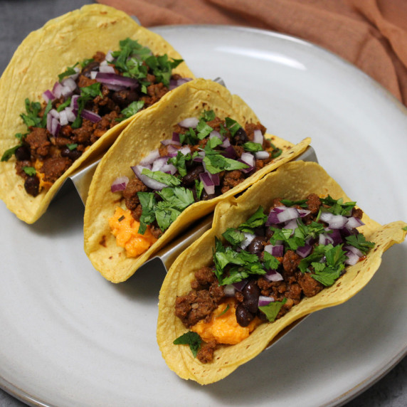 Three tacos made with black beans, chorizo, and sweet potato puree