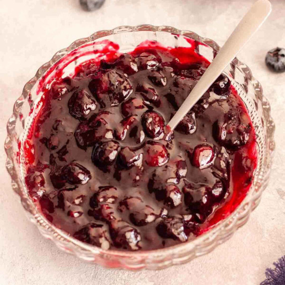 Blueberry cake filling in a bowl with a spoon.