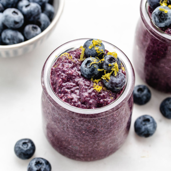 Lemon blueberry chia pudding in a glass jar with blueberries and lemon zest on top.