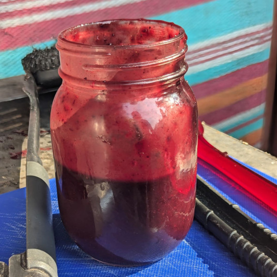 A mason jar filled with blueberry BBQ sauce. 