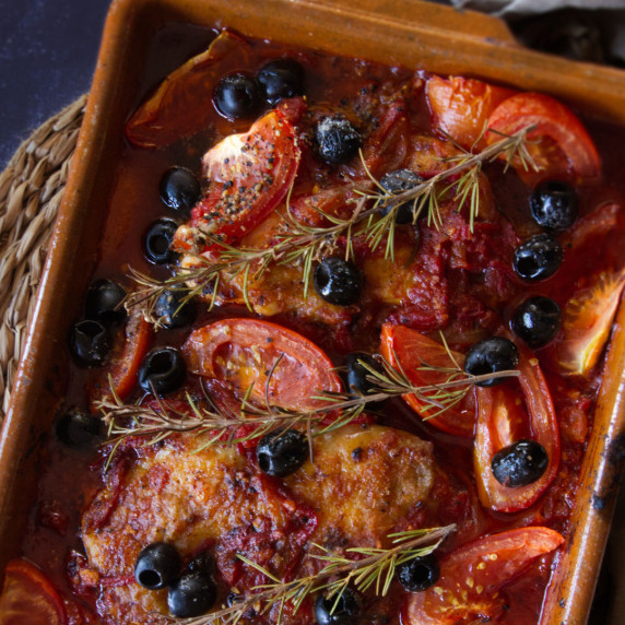 A large dish of Mediterranean chicken thighs cooked in a tomato sofrito.