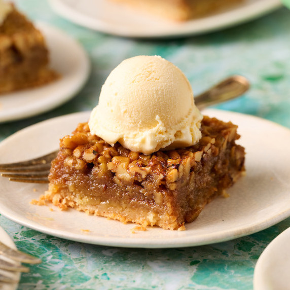 a pecan pie bar topped with ice cream on a plate