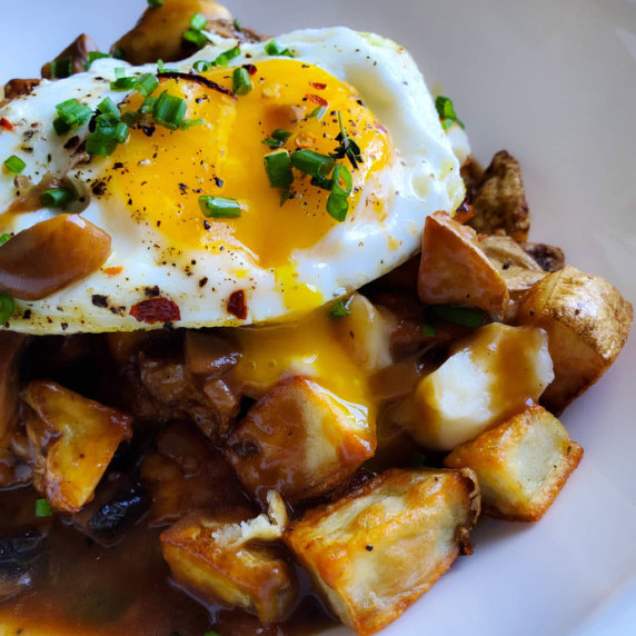 Crispy, golden potatoes smothered in brown gravy with a fried egg on top.