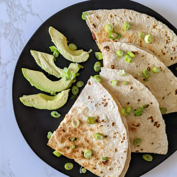 Quesadilla triangles on a plate with sliced avocado