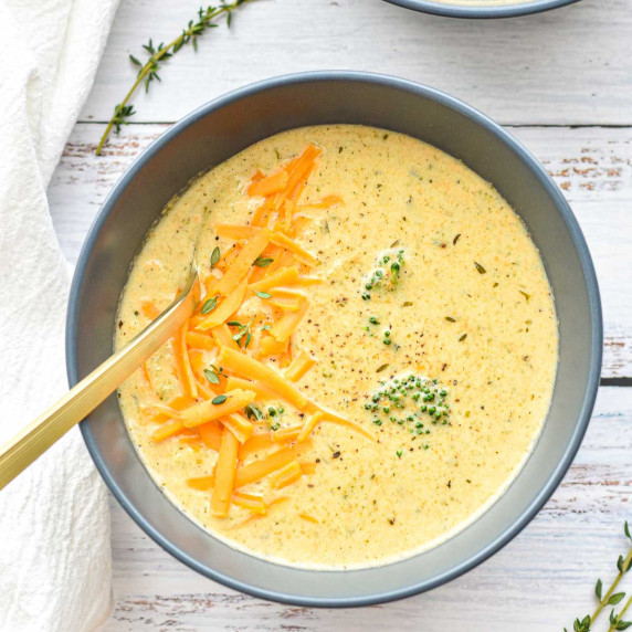 broccoli cheddar soup in a blue bowl with a spoon.