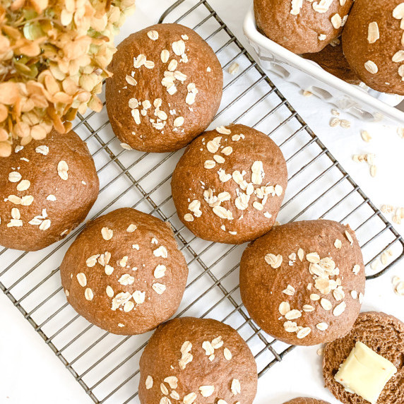 hearty brown bread rolls with oats on top on a wire cooling rack