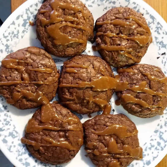 Seven brownie cookies with caramel drizzle on a plate.