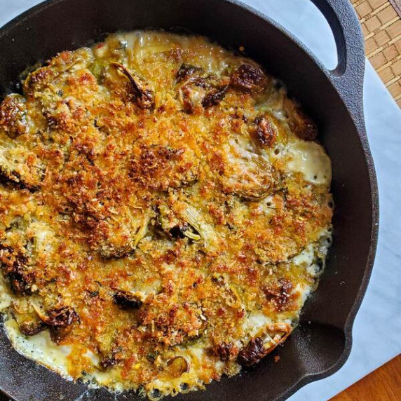 Golden brown skillet of brussel sprouts baked in cream.