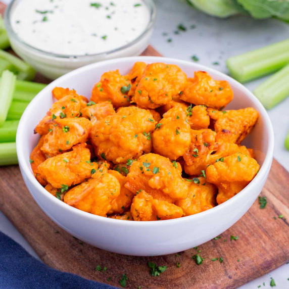 Buffalo Cauliflower Bites RECIPE served in a white bowl with celery and ranch.