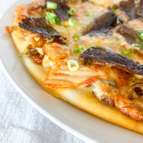 close up of kimchi and bulgogi pizza with green onions