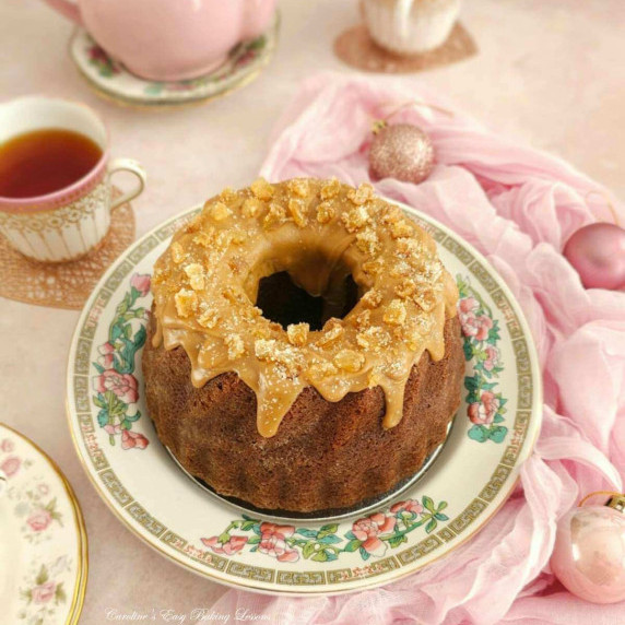 Angled shot of a pumpkin gingerbread bundt cake, topped with a golden butterscotch glaze.