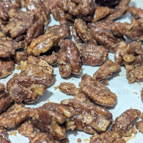 Candied pecans on a parchment lined pan. 