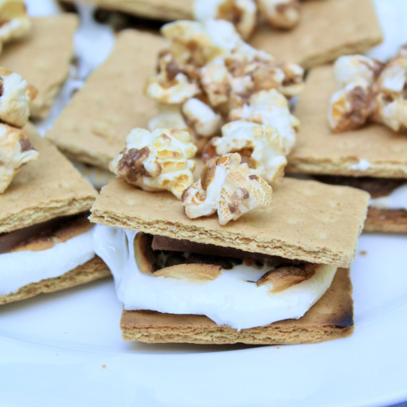 S'mores topped with Snickers flavored popcorn on a white plate.