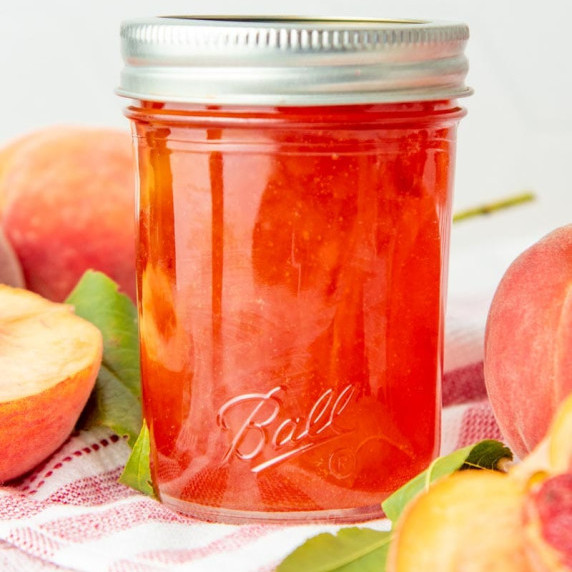 Close up of Ball smooth sided jelly jar filled with homemade bourbon peach jam.