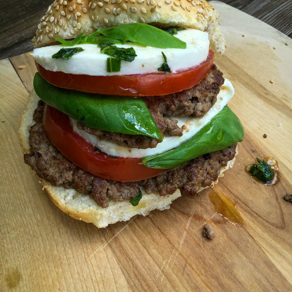 beef smash burgers layered with tomato, mozzarella, and basil with a bun