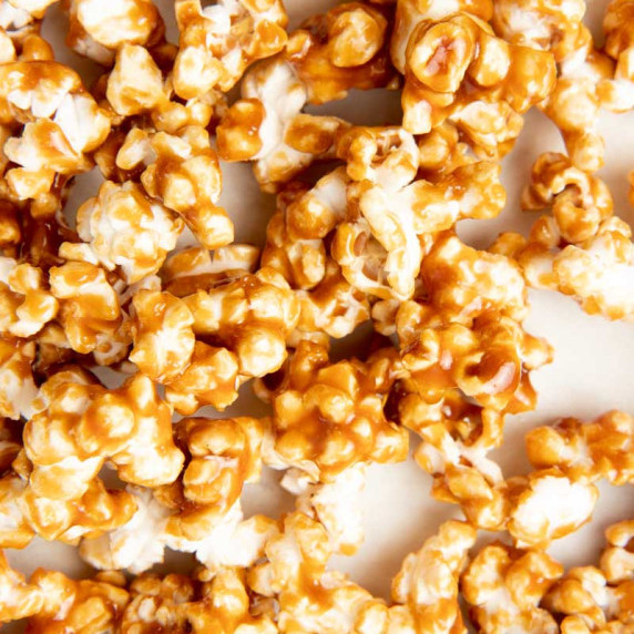 Overhead close view of caramel popcorn on a white counter.